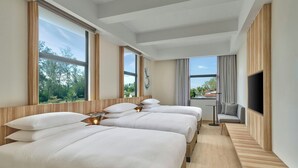 A hotel room with three beds, a TV, and large windows offering a view of trees and a building. - Fairfield By Marriott Kuala Besut (Kampong Raja)