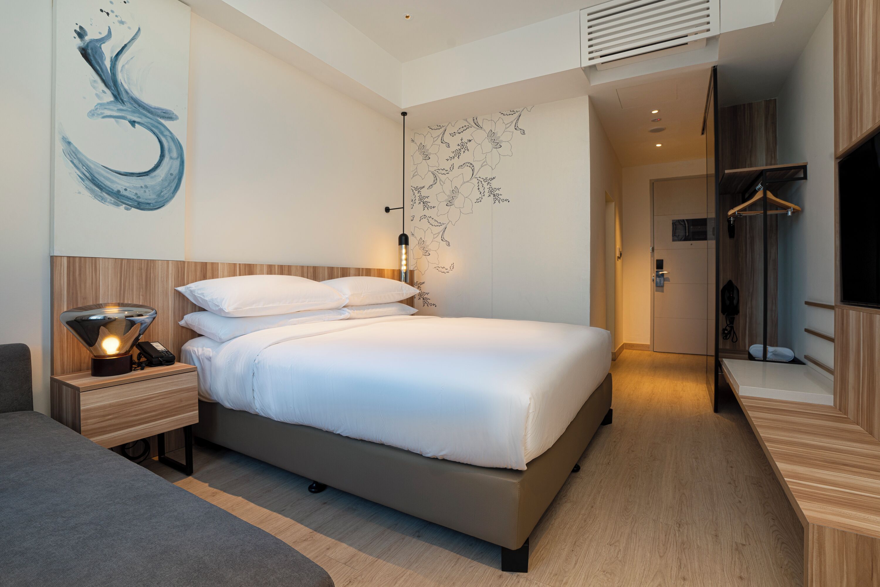Een moderne slaapkamer met een groot bed, nachtkastjes, een kunstwerk aan de muur en een kledingkast.