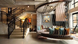Un intérieur moderne agrémenté d’un escalier en colimaçon, d’un fauteuil suspendu et d’un coin salon confortable avec des coussins.