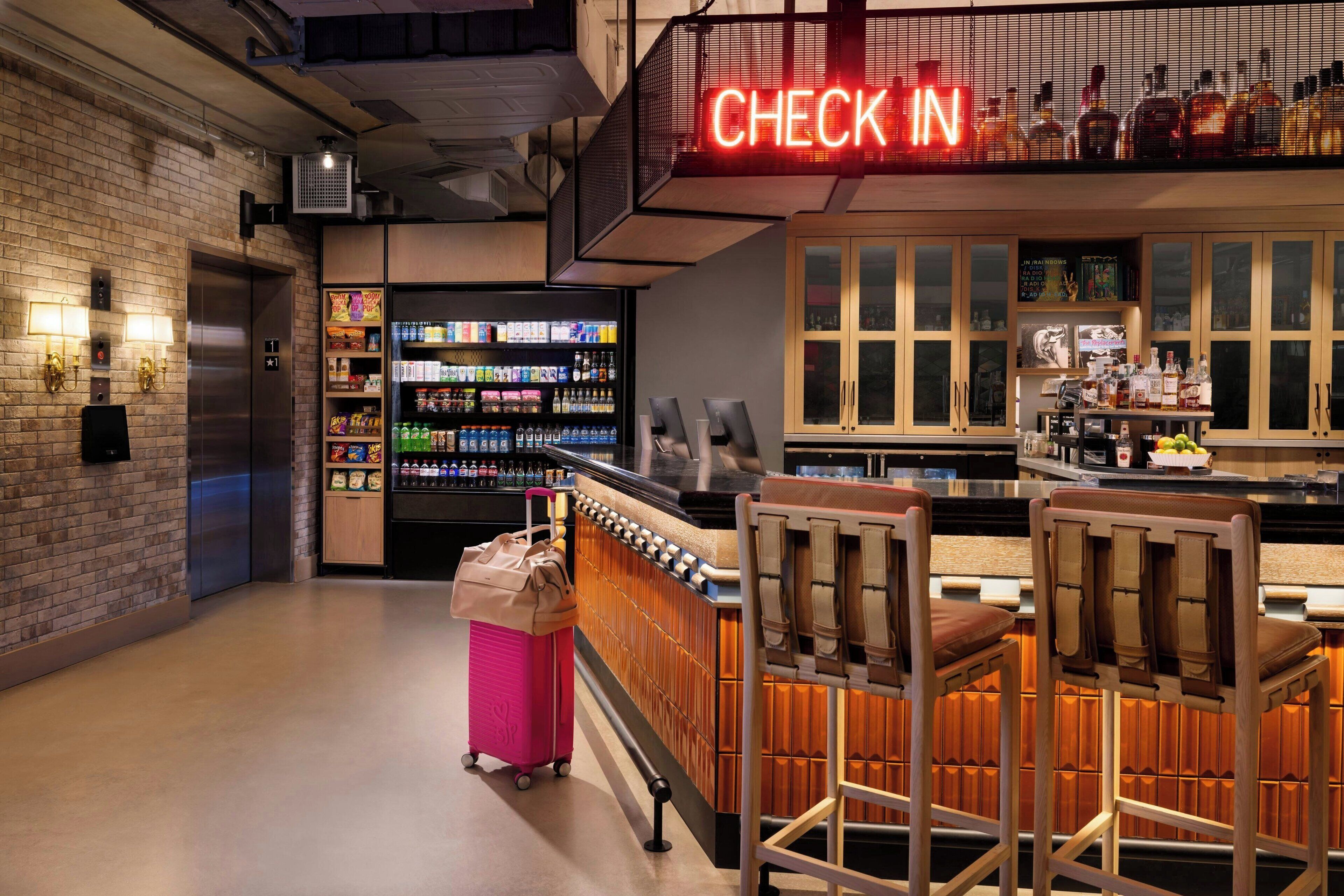 A bar area with a neon 'CHECK IN' sign, a vending machine, and a bar counter with stools.