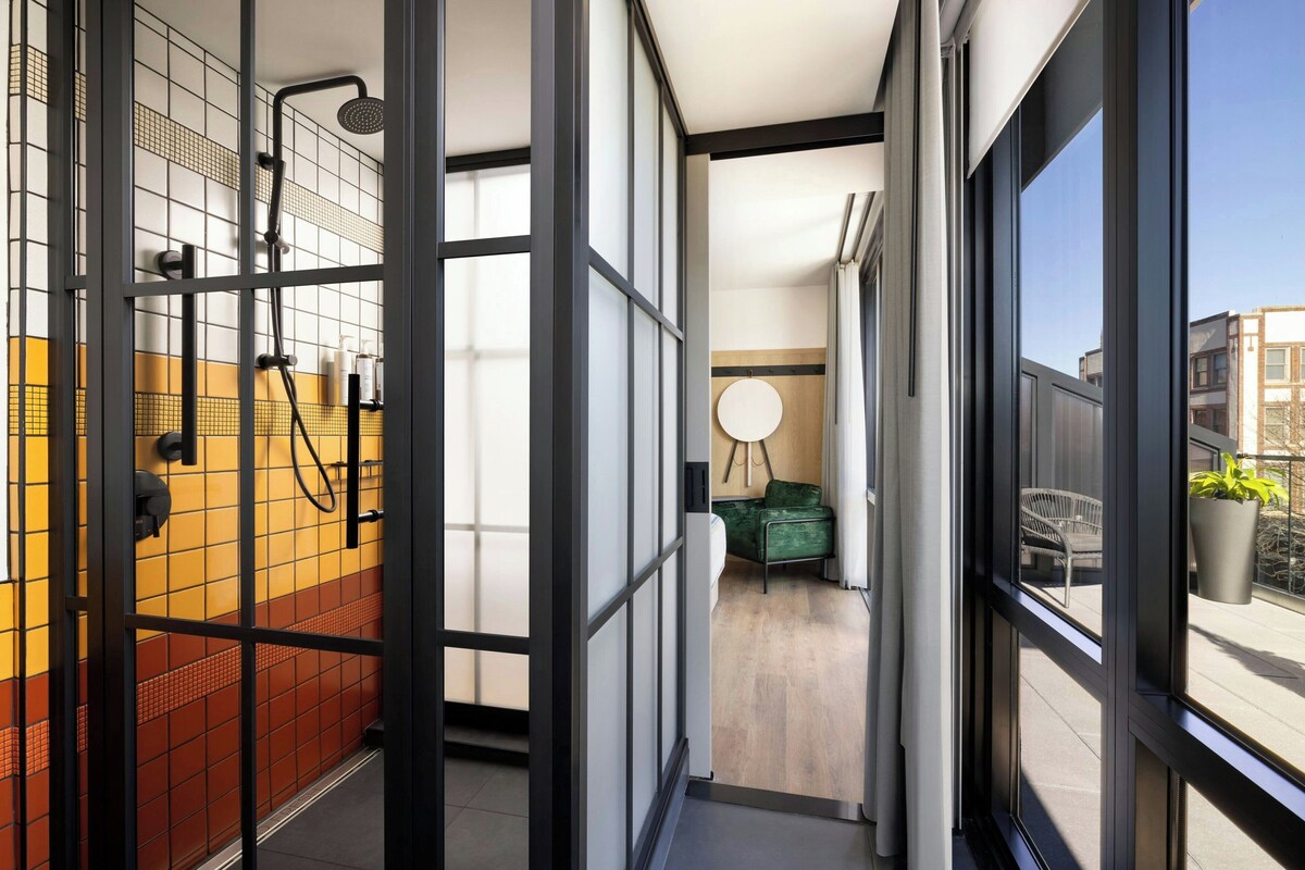 A modern bathroom with a shower, a toilet, and a sink. There is a window with a view of the outside.