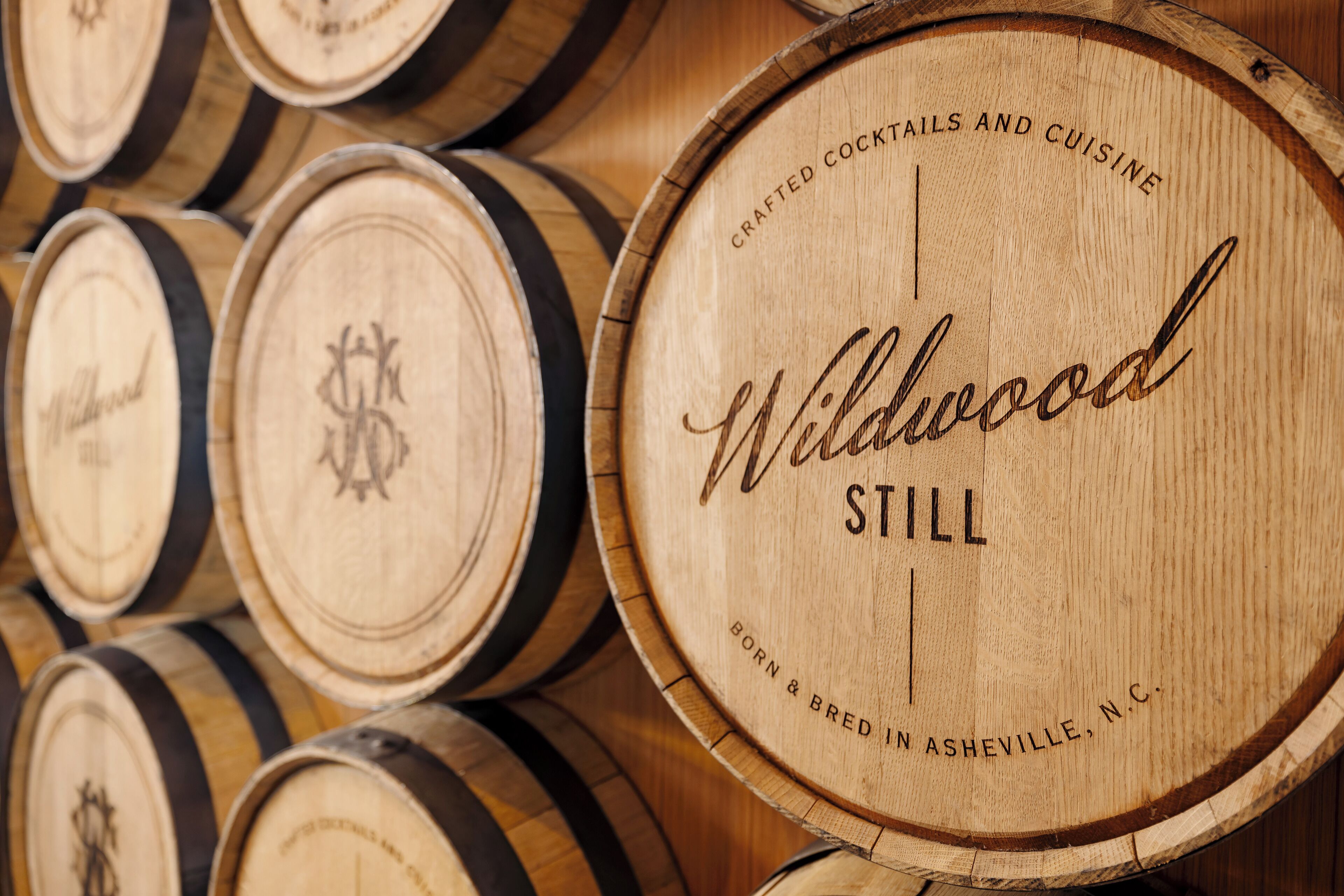 A close-up of wooden barrels with the text "Wildwood Still" and "Crafted Cocktails and Cuisine" on them.