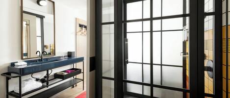 A modern bathroom with a glass shower enclosure, a black-framed mirror, and a blue countertop with a towel rack.