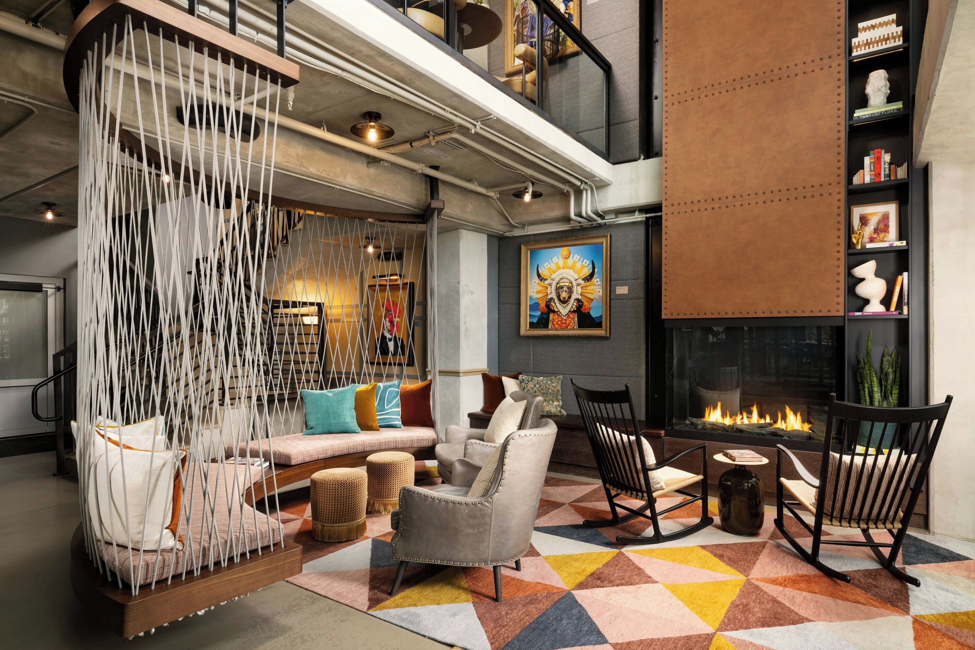 Un salon moderne comprenant un canapé, des fauteuils, un tapis à motifs et une cheminée.