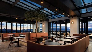 Un salon moderne avec des fauteuils en cuir, des tables et un grand arbre.