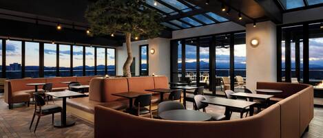 A modern lounge with leather seating, tables, and a large tree.