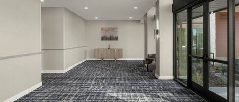 A hallway with patterned carpet, a bench, and a wall-mounted artwork.