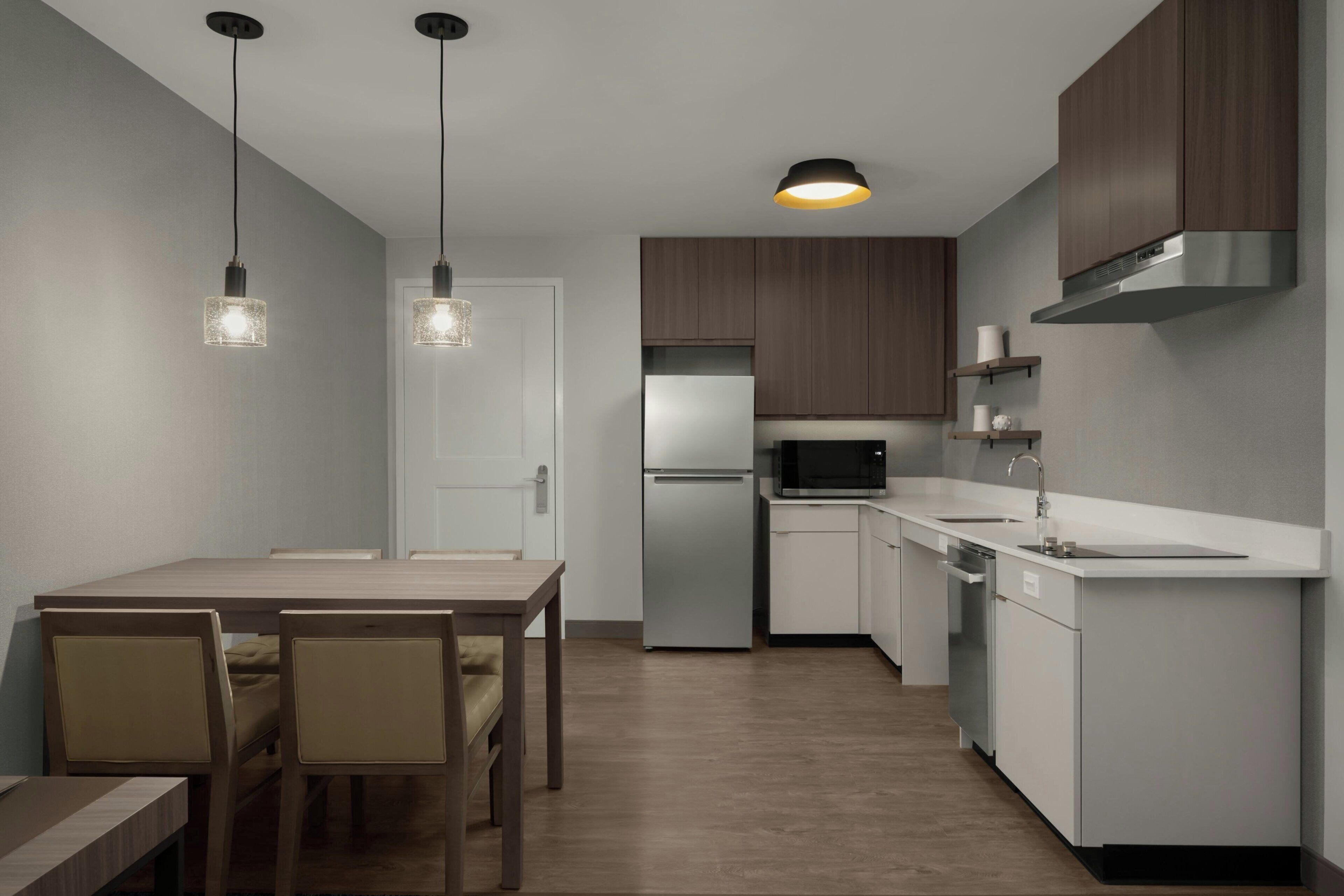 A modern kitchen with a central island, stainless steel appliances, and pendant lighting.