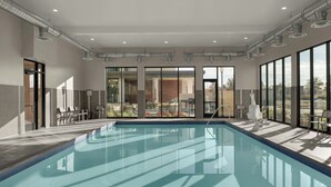 Una piscina coberta moderna amb parets de vidre transparent, un paviment de rajola i vista a l'exterior.