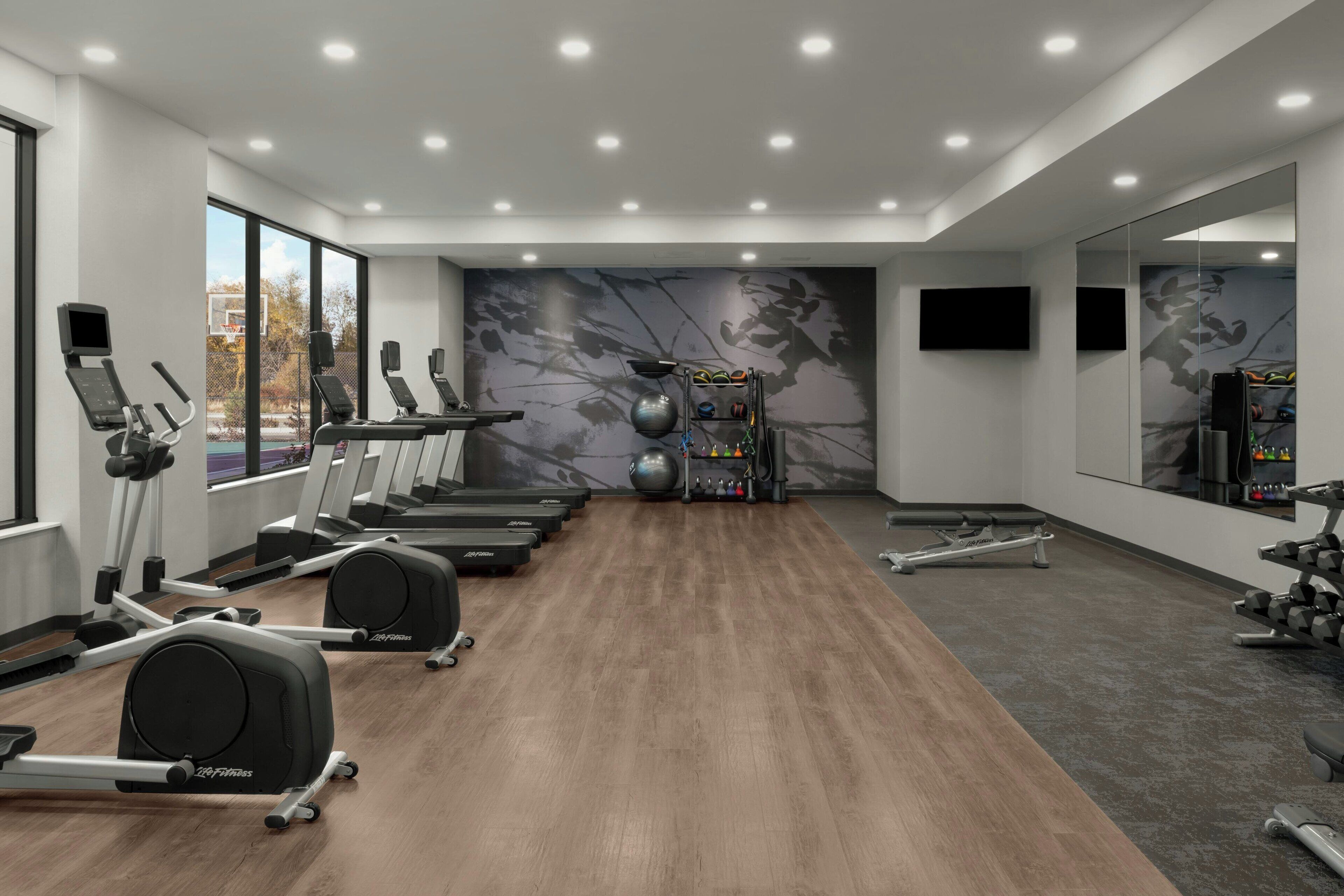 Un gimnasio moderno con cintas de correr, elípticas y pesas libres.