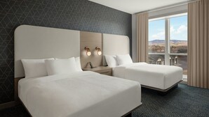 Habitació d'hotel amb dos llits, una finestra gran que dona a una vista i una paret amb un disseny geomètric.