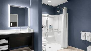 A modern bathroom with a large mirror, white sink, and a walk-in shower.