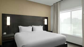 Een moderne hotelkamer met een groot bed, twee nachtkastjes en een raam met gordijnen.