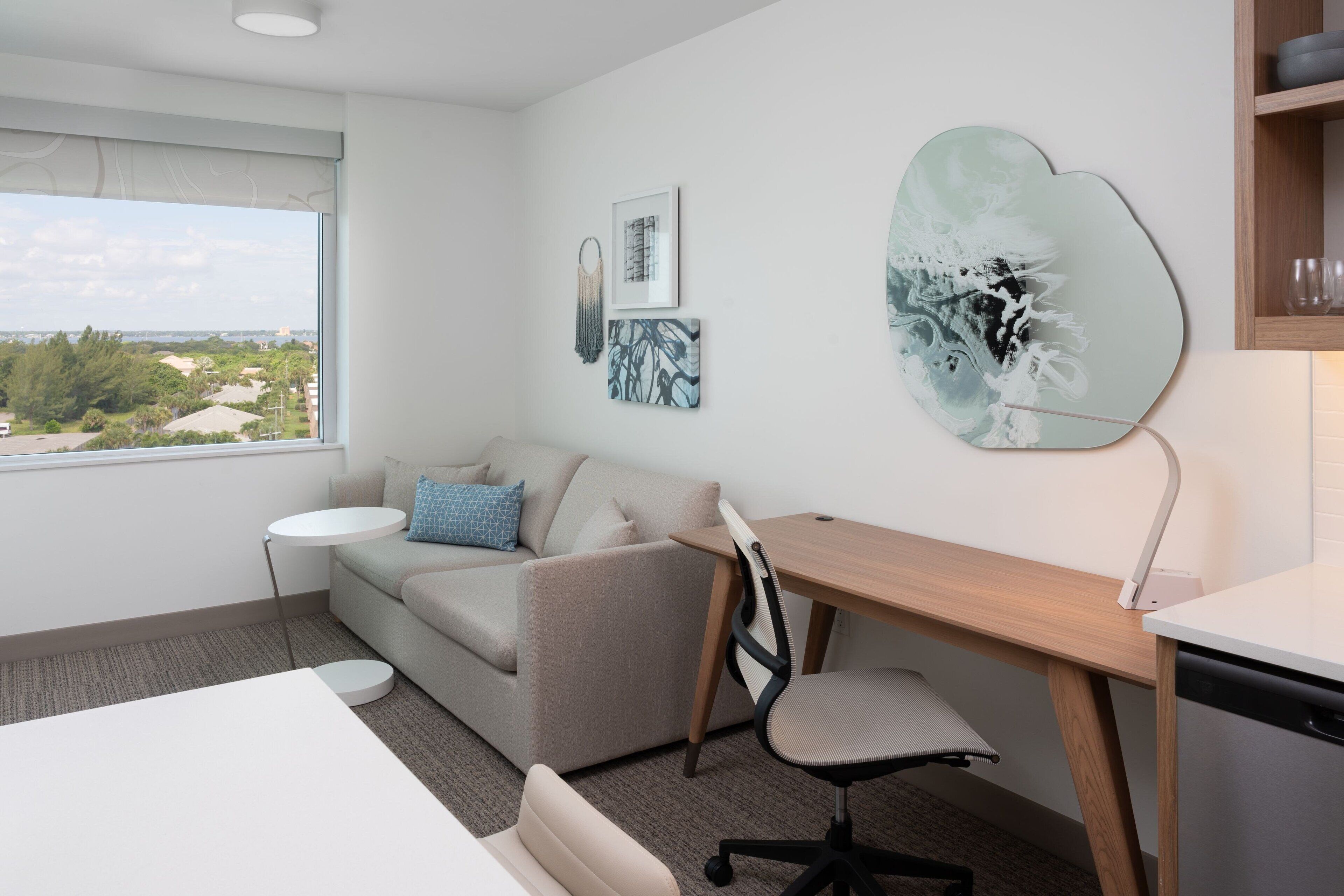 A modern room with a sofa, a desk, and a view of the city.