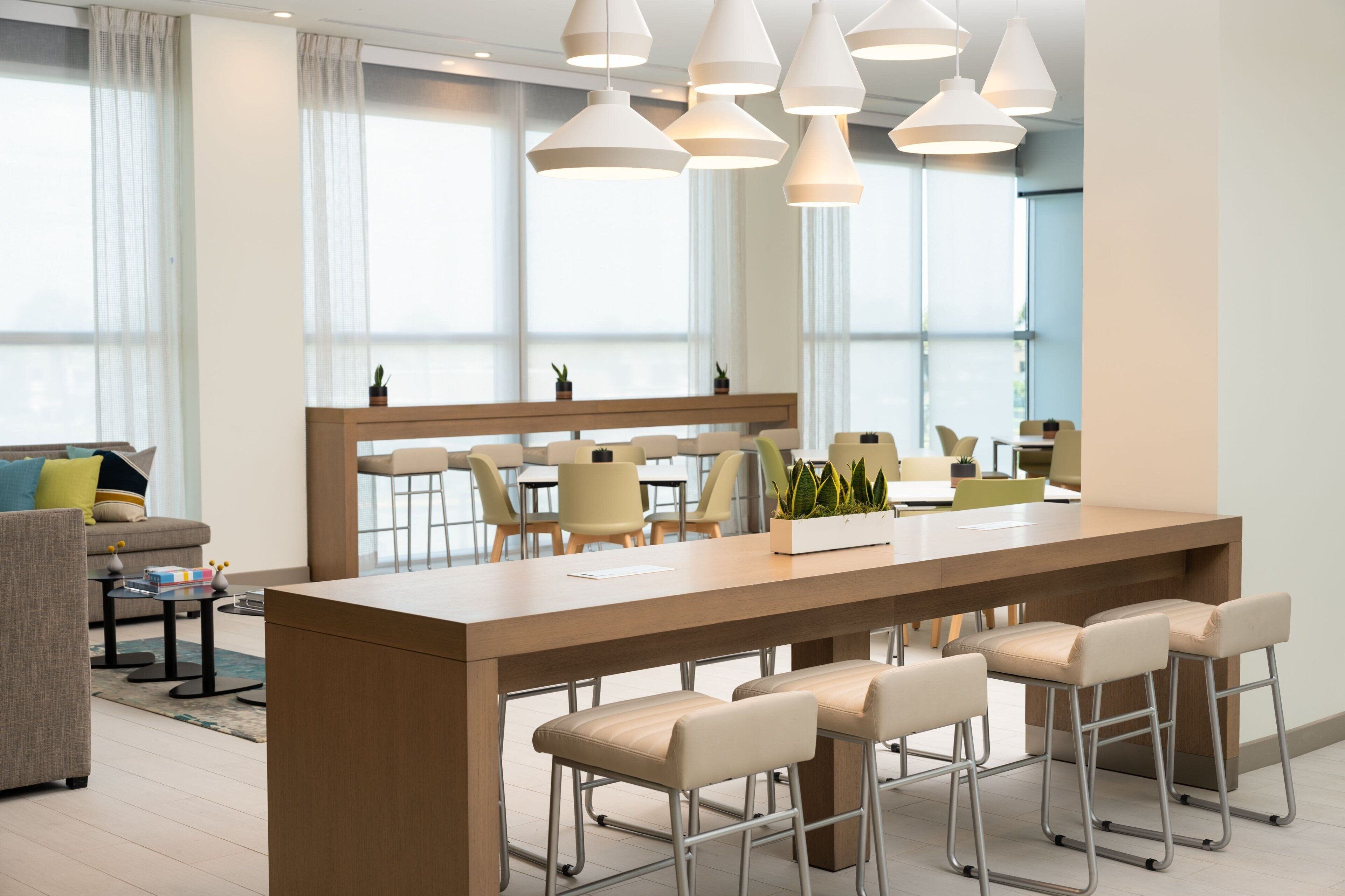 A modern kitchen with a central island, bar stools, and pendant lighting.