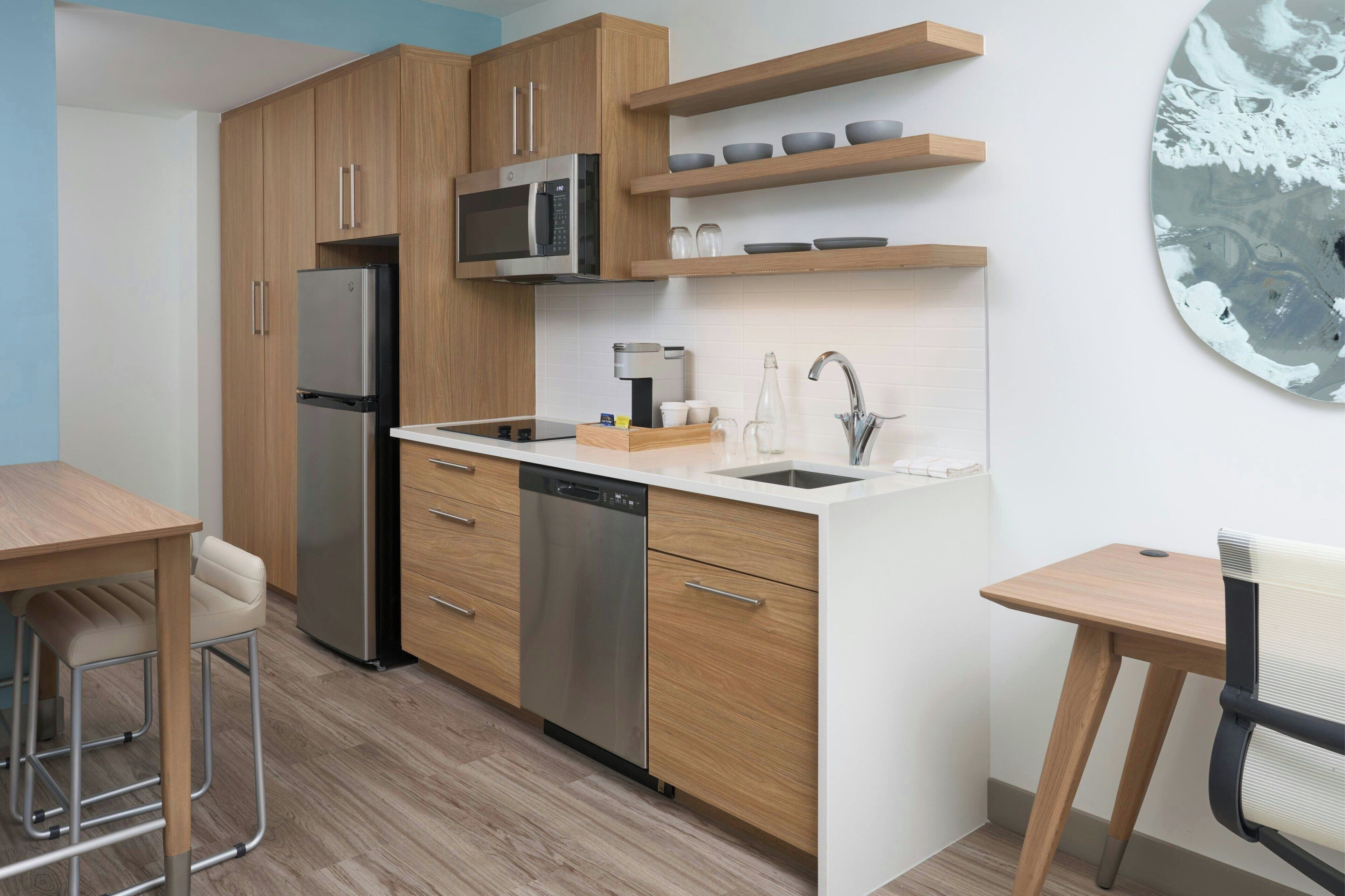 Eine moderne Küche mit Holzschränken, Edelstahlgeräten und einer weißen Arbeitsplatte.