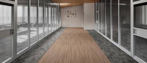 A modern hallway with glass doors, a wooden ceiling, and a carpeted floor.