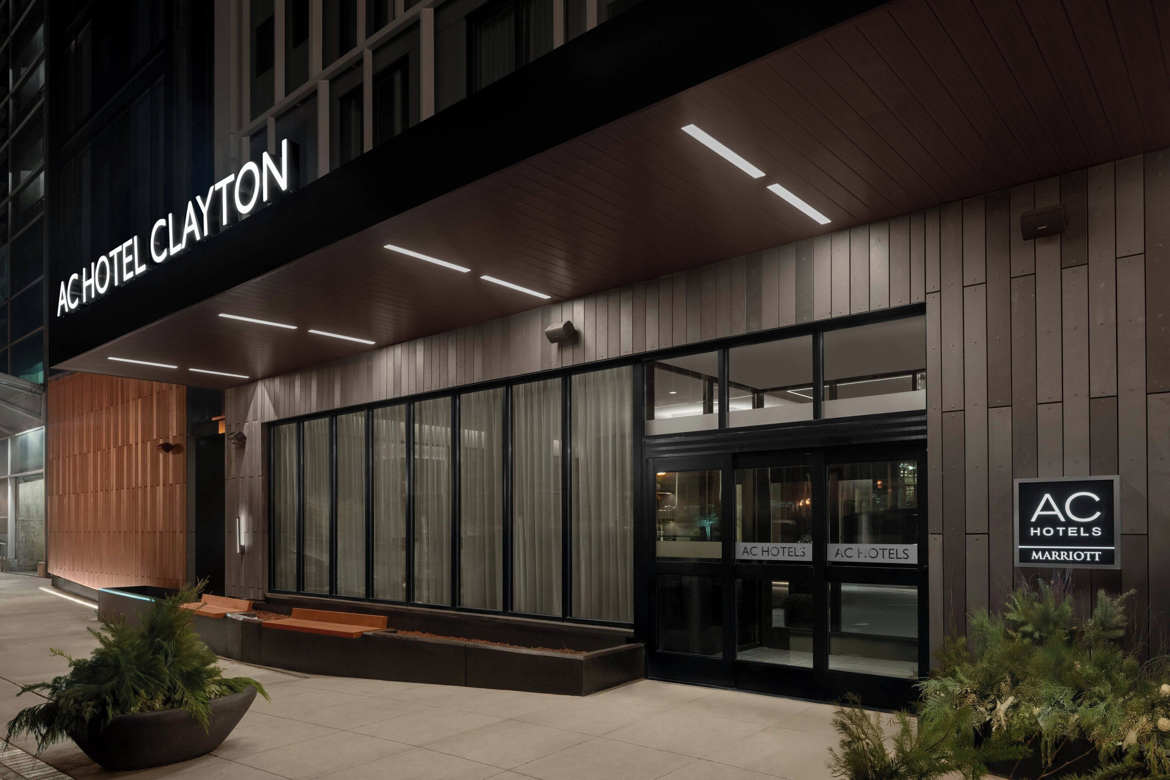 A modern hotel exterior with a large entrance, glass doors, and a sign indicating it is part of the AC Hotels Marriott chain.