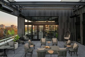 Una terraza en la azotea con mobiliario exterior moderno, una chimenea y vistas de la ciudad.