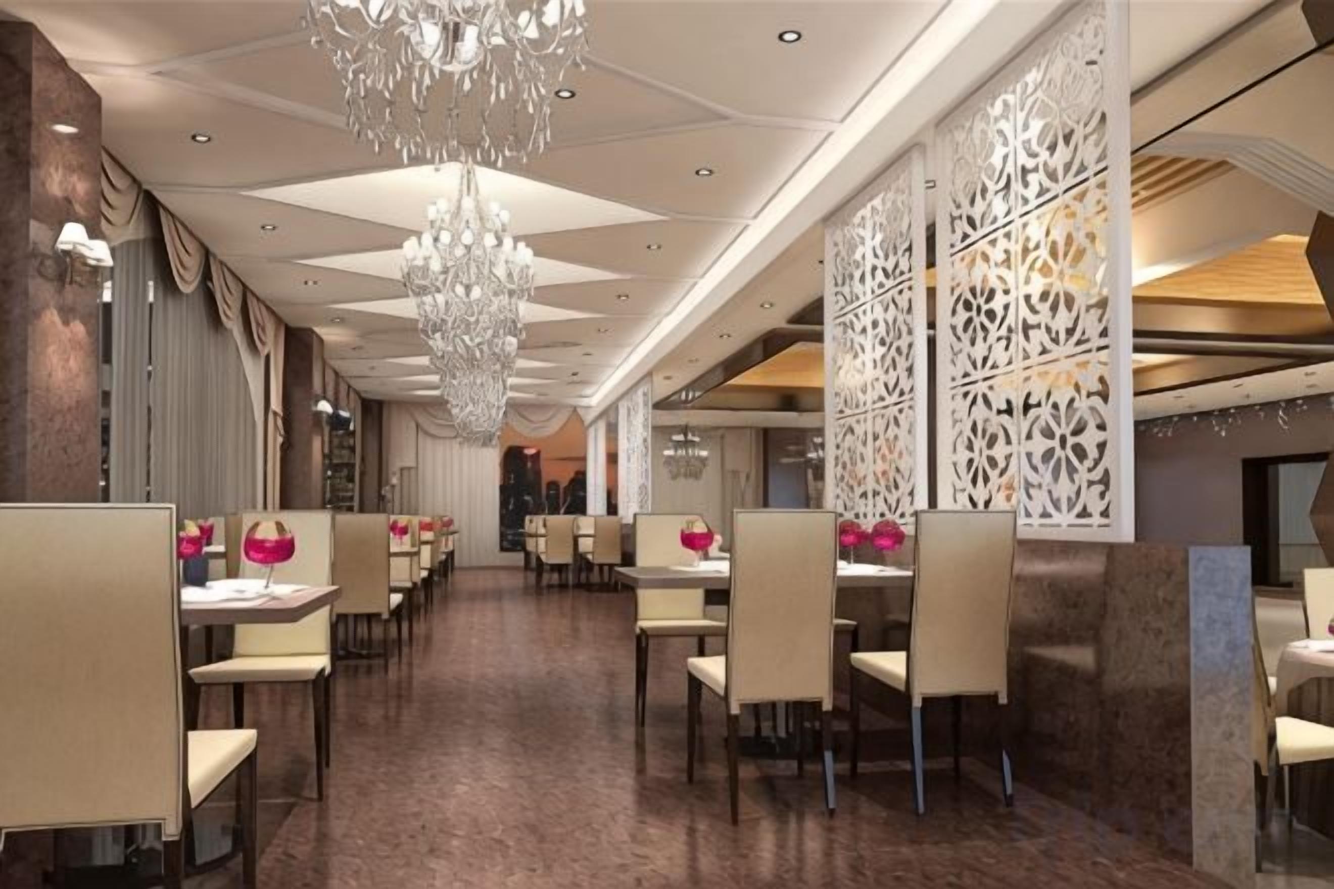 A restaurant with a long counter, multiple tables, and a decorative ceiling.