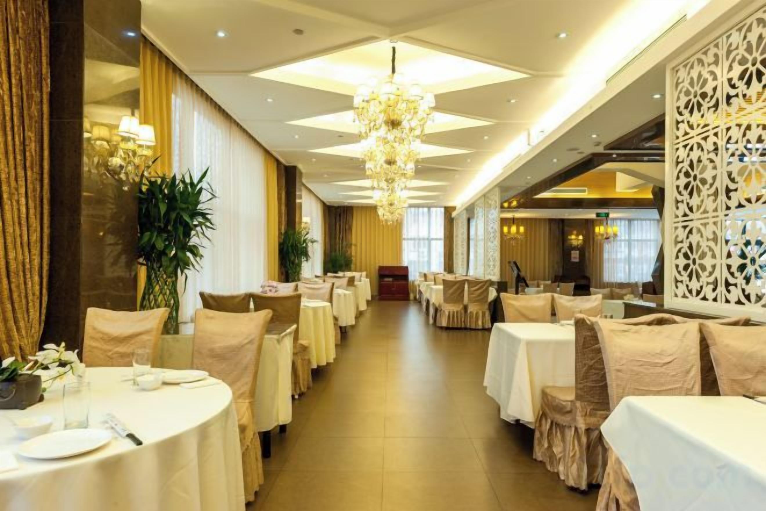 Un comedor de hotel con mesas redondas, candelabros y un largo pasillo.