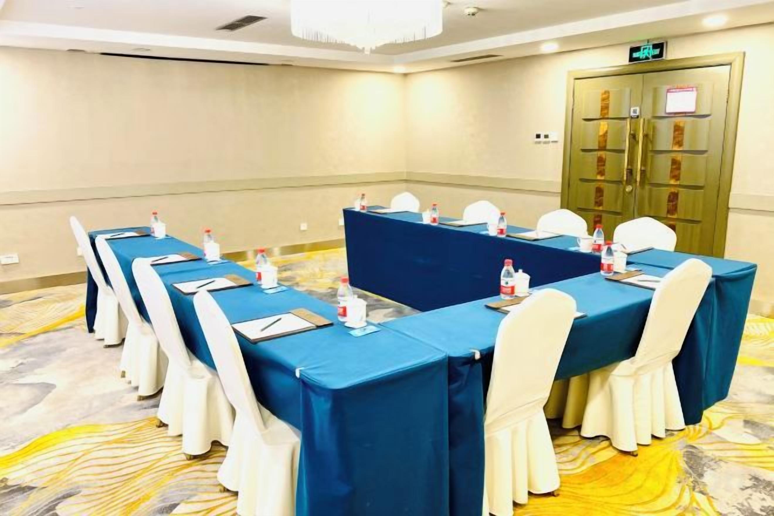 A conference room with a long table, chairs, and a blue tablecloth.