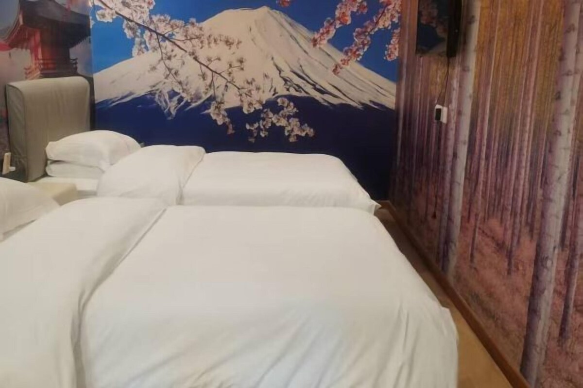 Ein Hotelzimmer mit zwei Betten, einem Holzschrank und einer Wandmalerei vom Berg Fuji.