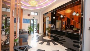 Eine Hotelhalle mit Empfangstresen, Sitzgelegenheiten und einem rund gemusterten Boden.