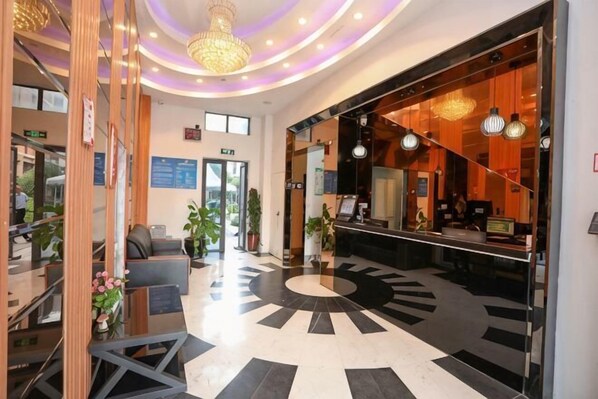 A hotel lobby with a reception desk, seating area, and a circular patterned floor.