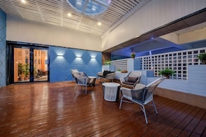 An indoor patio with wooden flooring, a seating area with chairs and a table, and a view of the outside. - Suiyuan Chuangxiang Hotel (Ningbo Qinglinwan Branch) (Ningbo)