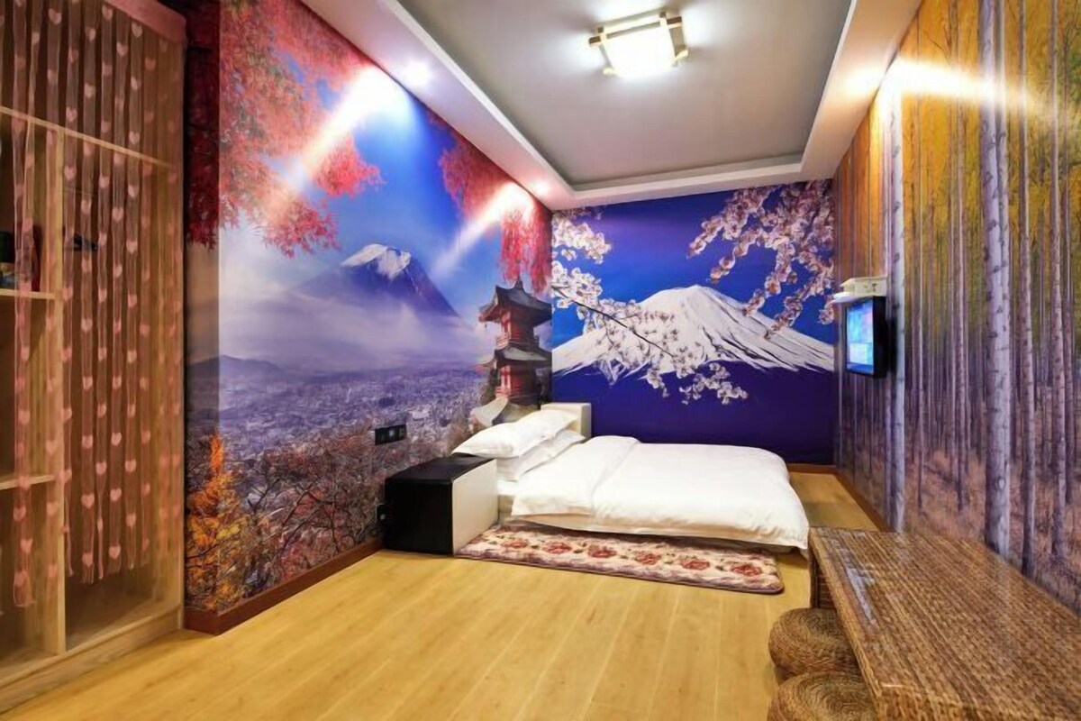 Ein Zimmer mit einem Bett, einem Fernseher und einem Wandbild einer Berglandschaft.