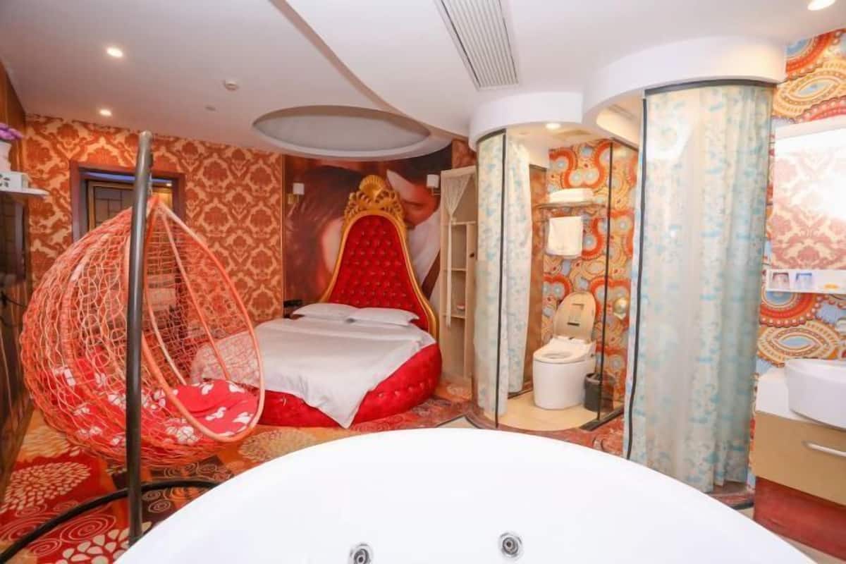 Une pièce comprenant un lit, un fauteuil suspendu, une baignoire et un espace douche.