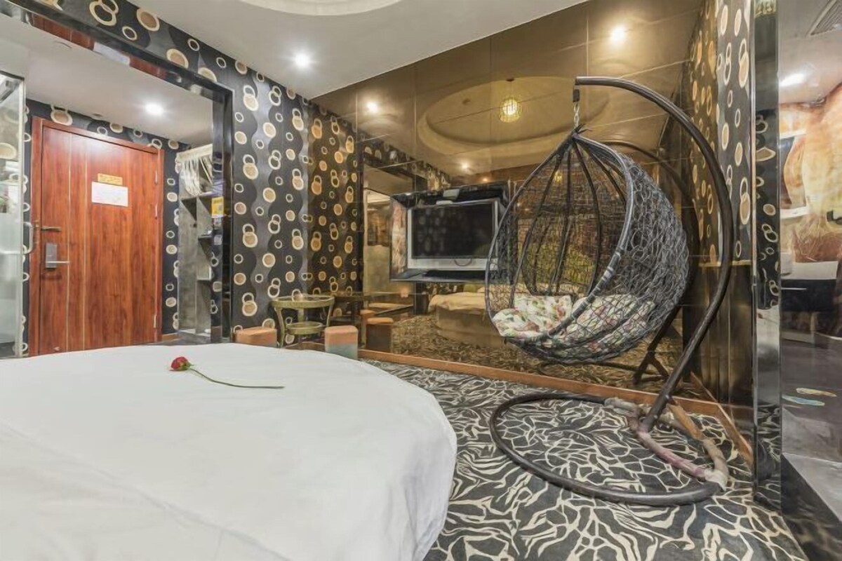 Une pièce avec un lit, un fauteuil suspendu, une télévision et un sol à motifs.