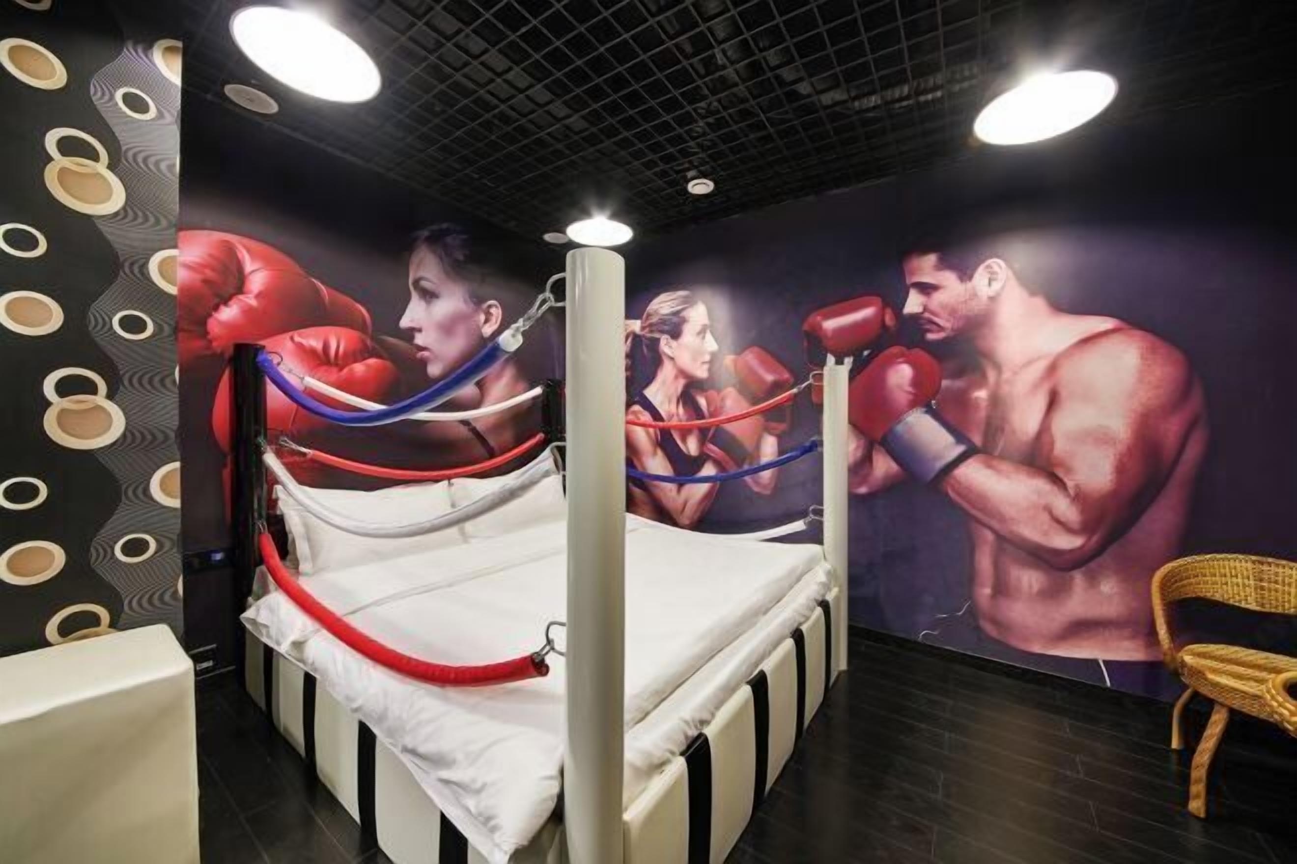 Ein Zimmer mit einem Bett, einem Sandsack und einem Wandgemälde eines Boxers.
