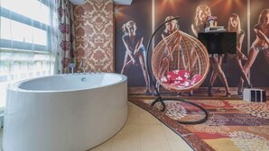 Ein modernes Badezimmer mit einer großen Badewanne, einem Hängekorbsessel und einer Wand mit einem Poster.