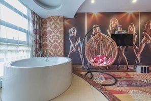 Ein modernes Badezimmer mit einer großen Badewanne, einem Hängekorbsessel und einer Wand mit einem Poster.