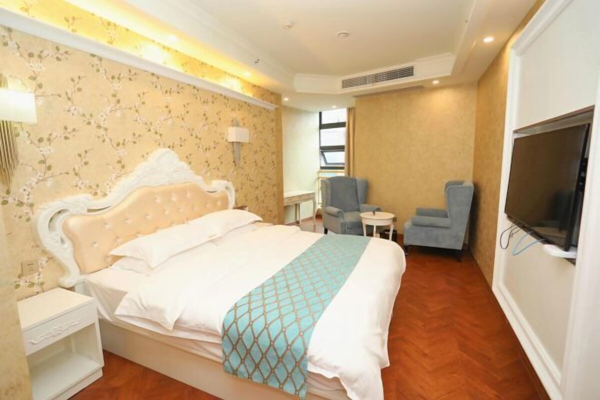 Une chambre d’hôtel avec un lit, une chaise, une télévision et une petite table.