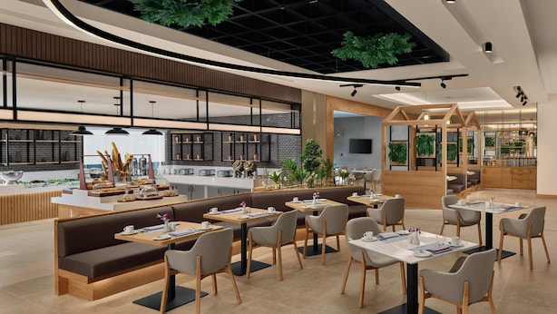 En moderne restaurant med buet loft, træsæder og et køkken i baggrunden.