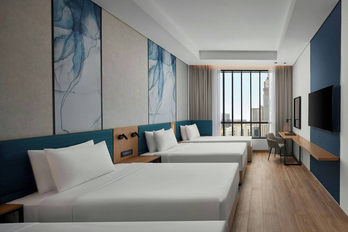 Una habitación de hotel con dos camas, un escritorio, una silla y un televisor.