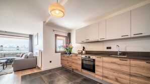A modern kitchen with wooden cabinets, a built-in oven, and a large window overlooking a snowy landscape.
