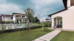 Zona residencial con piscina, paseo empedrado y área de estar al aire libre techada.
