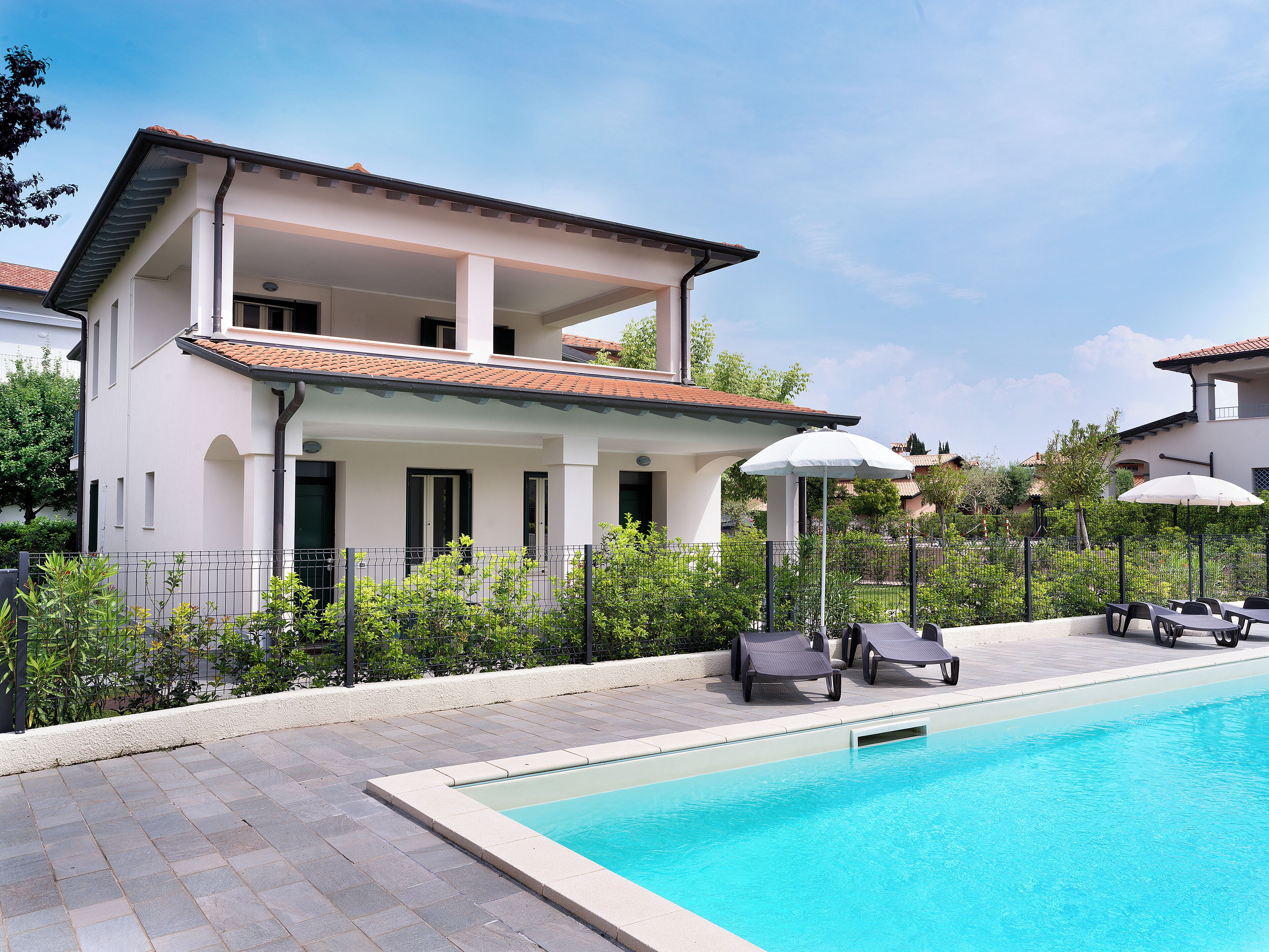 A modern two-story house with a swimming pool, outdoor seating, and a well-maintained garden.