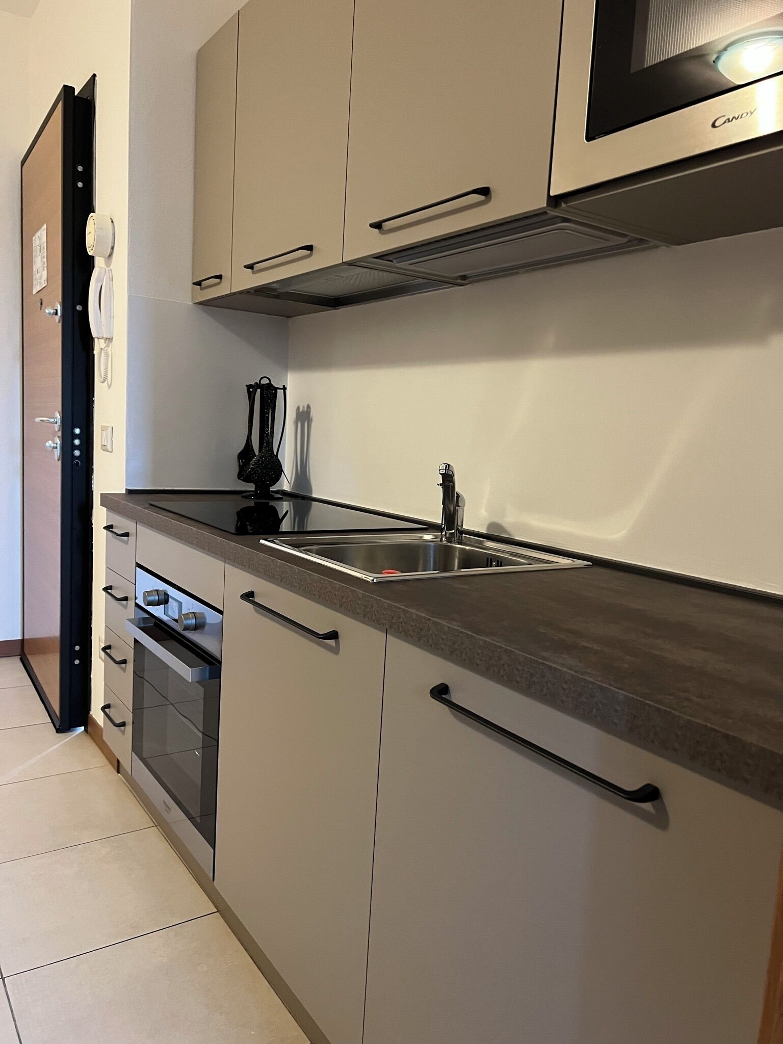 Una cocina moderna con horno empotrado, microondas y lavamanos.