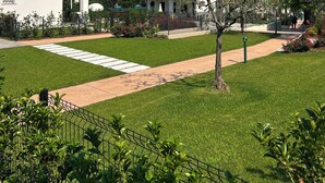 Un edificio moderno con fachada blanca y tejado de tejas rojas, rodeado de césped cuidado y un sendero pavimentado.