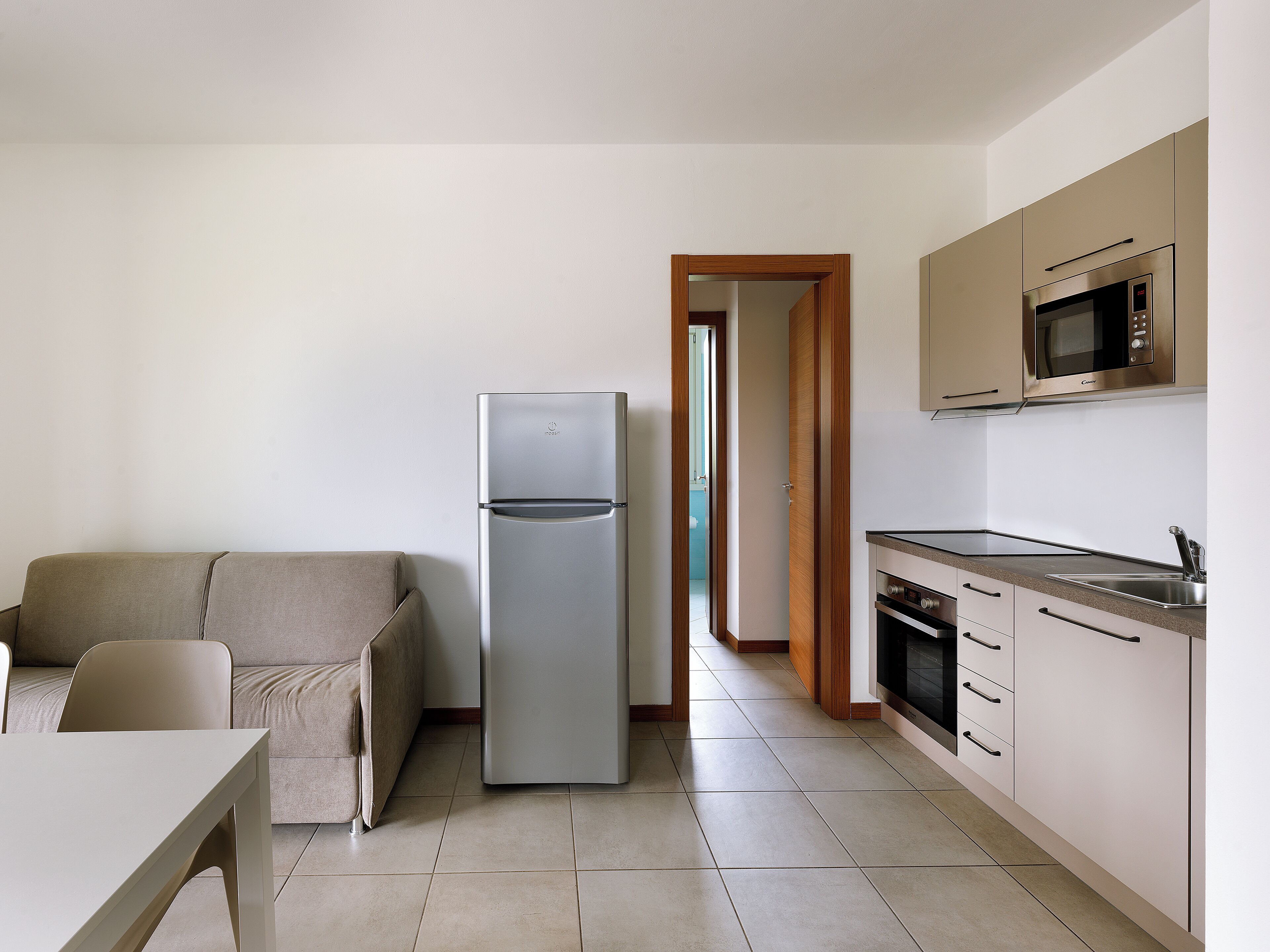 Eine moderne Küche mit Einbau-Mikrowelle, Backofen und Kühlschrank. Es gibt einen Essbereich mit Tisch und Stühlen.