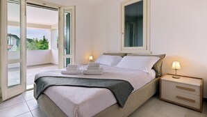 Un dormitorio con cama, dos lámparas de noche, una mesita de noche y vistas a través de una puerta abierta.