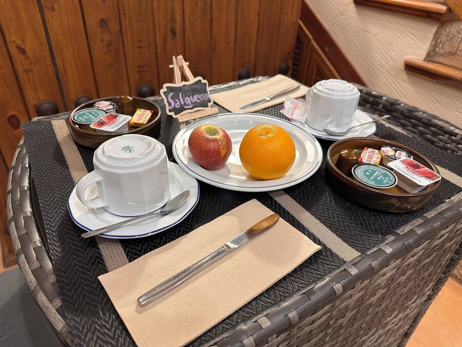 A wicker table with a plate of food, a cup, a spoon, a napkin, and a small chalkboard sign.