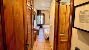 A hallway with wooden doors and a bed in the distance. - Hotel Posada La Fragua (Pinuecar-Gandullas)