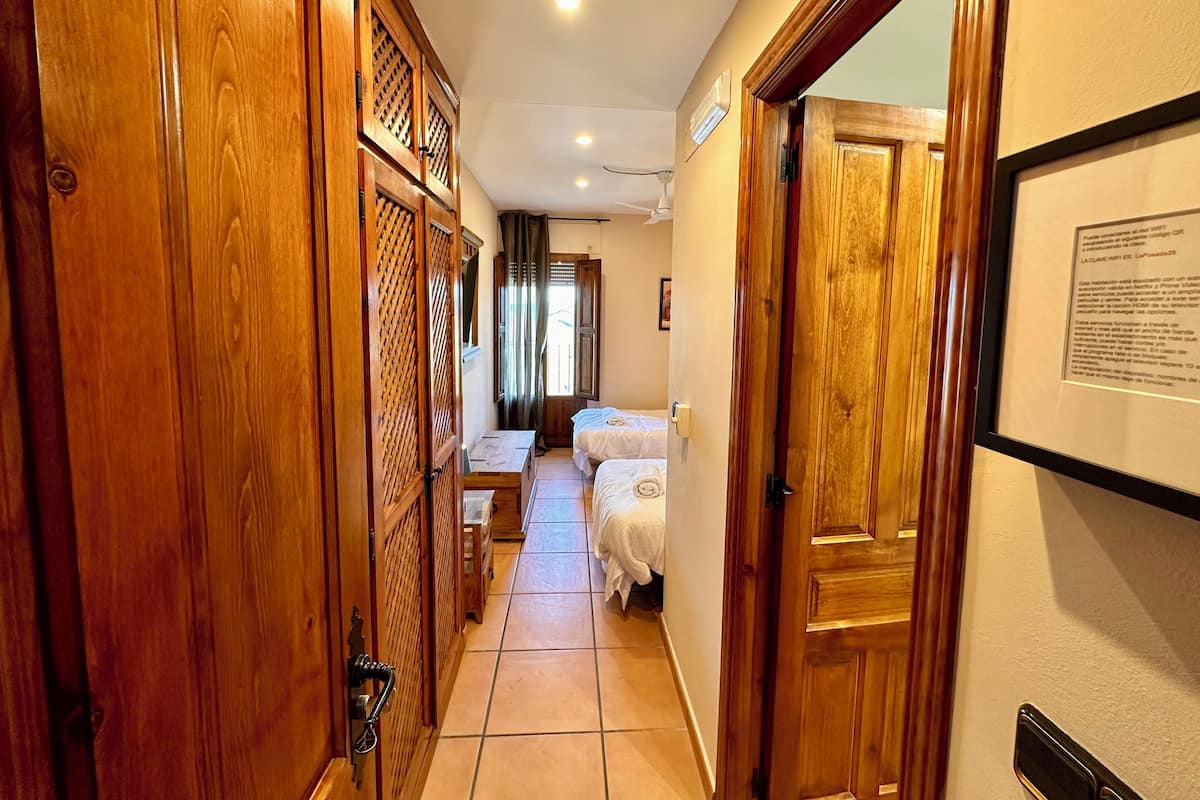 Un pasillo con puertas de madera y una cama al fondo.