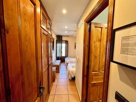 Un pasillo con puertas de madera y una cama al fondo.
